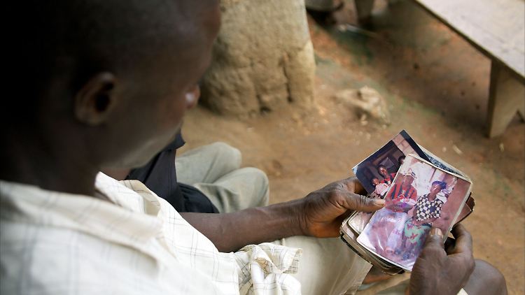 Etienne Ouamouno mit einem Foto, das ihn mit seiner Frau Sia Dembadouno und Sohn Emile zeigt. Emile wurde am 28.12.2013 das erste Opfer des schlimmsten bekannten Ebola-Ausbruchs der Geschichte.