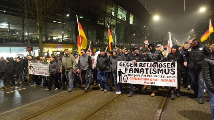 Pegida-Demonstranten ziehen in Dresden am Stadion des Drittligisten Dynamo vorbei.