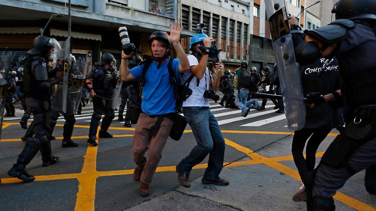 Proteste in São Paulo - von Polizisten umgebene Fotografen erheben die Hände.