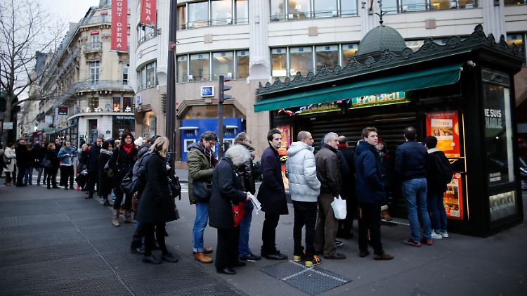 Eine lange Schlange vor einem Kiosk in Paris.