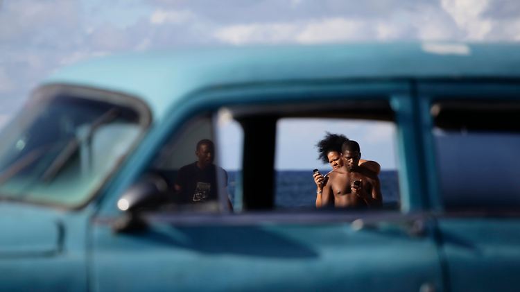 Alter Straßenkreuzer und Mobiltelefone am Strand von Havana.