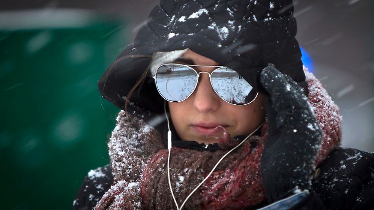 Mit Sonnenbrille in den Blizzard? "Wie denn sonst?". mag sich diese Dame denken, als sie im einsetzenden Schneetreiben die First Avenue überquert.