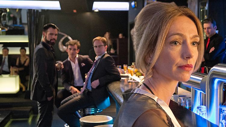 Drei feierwütige Banker beobachten die Kunstprofessorin Claudia Denk.