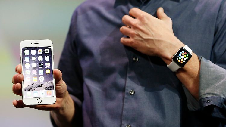 Und so soll sie aussehen: Im vergangenen September führte Appple-Chef Tim Cook (nicht ganz im Bild) die neue Smartwatch (r.) zusammen mit dem iPhone 6 Plus (l.) vor.