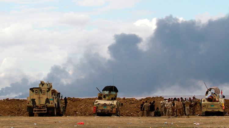 Irakische Soldaten beobachten den Brand der Ölquellen.