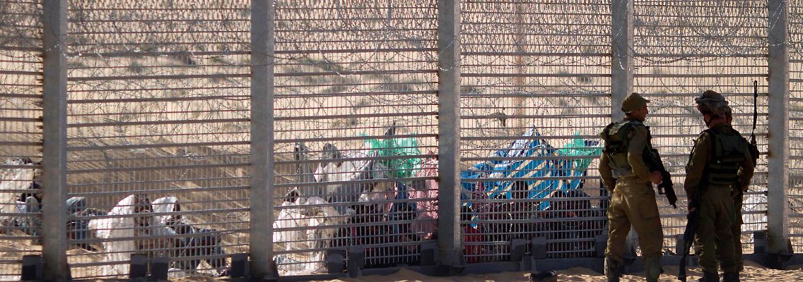 Afrikanische Flüchtlinge warten hinter dem Grenzzaun, den Israel von Ägypten trennt.