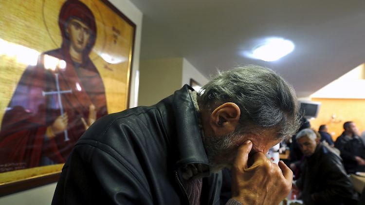Ein Mann spricht vor seinem Mittagessen in der Suppen-Küche der Orthodoxen Kirche "Galini" ein Tischgebet.