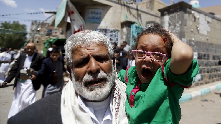 Ein Mann trägt ein verletztes Mädchen in Sanaa. Unter der Konkurrenz der Terroristen leiden vor allem Unschuldige. 