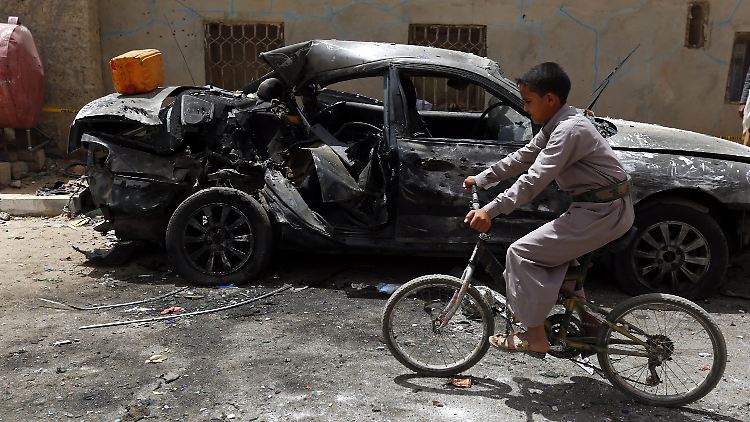 Ein Junge passiert ein bei den Anschlägen in Sanaa zerstörtes Auto.