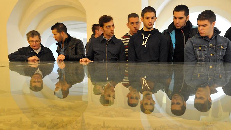 Junge Spanier betrachten in Ulm das Modell der Stadt in einer Vitrine: Auf Initiative der Handwerkskammer werden die in ihrer Heimat Arbeitslosen bei Ulmer Betrieben ausgebildet.