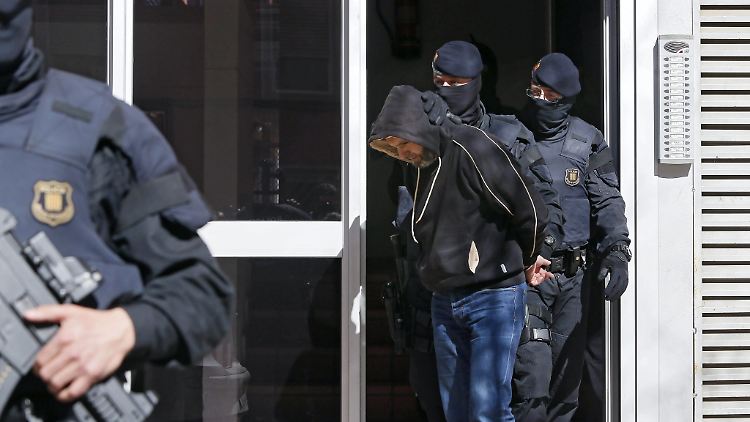 Spanische Polizeibeamte führen einen der Verdächtigen nach der Stürmung des Gebäudes nordöstlich von Barcelona ab.