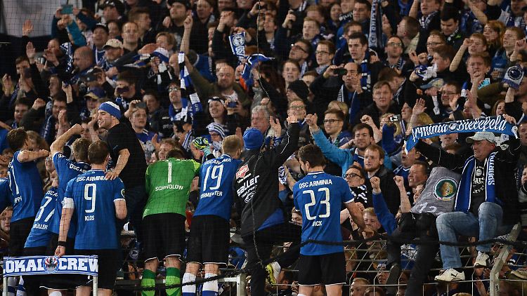 Helden wir ihr: Die Arminen feiern ihren Pokalcoup über Gladbach auf dem Zaun - und Bielefeld feiert mit.