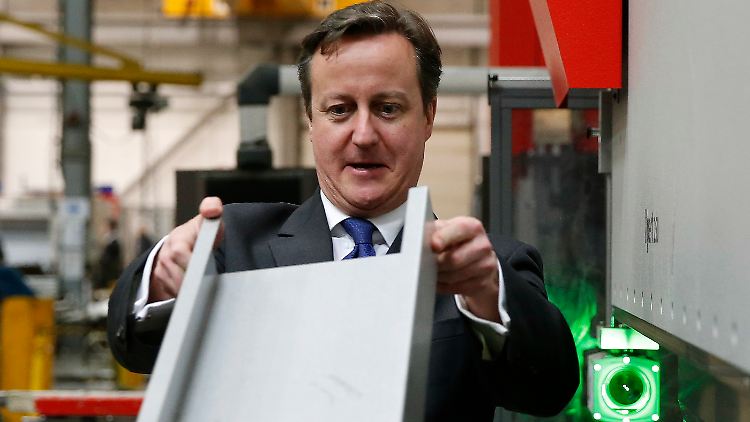David Cameron begutachtet während einer Fabrikbesichtigung ein Metallwerkstück.