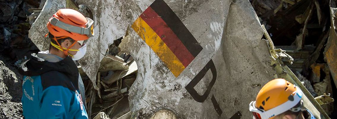 Rettungshelfer sichern ein Trümmerteil des abgestürzten Flugzeuges.