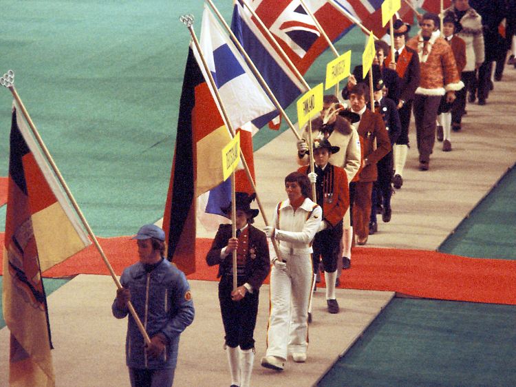 Ulrich Wehling (lnks) trägt beim Einzug zur Abschlussfeier der XII. Olympischen Winterspiele von Innsbruck im Jahr 1976 die Flagge ihres Landes.