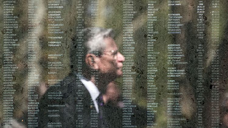Joachim Gauck spiegelt sich in einer Gedenktafel auf dem Friedhof in Schloss Holte-Stukenbrock. Auf der Tafel stehen die Namen der dort beerdigten sowjetischen Soldaten.