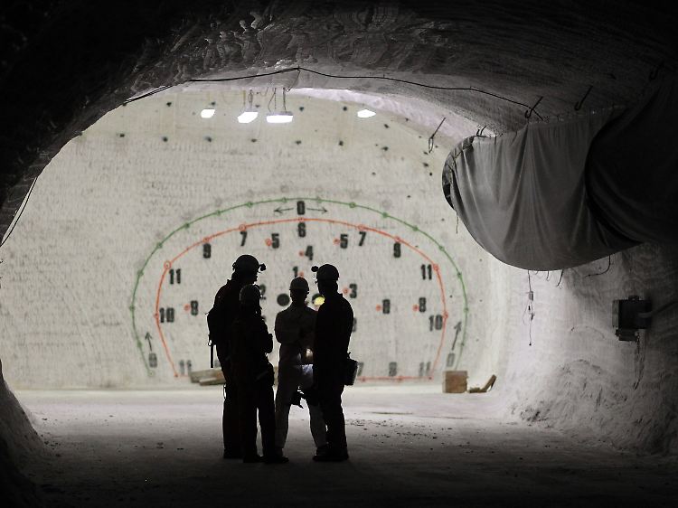 Bergarbeiter in einem Seitenstollen vor einer Wand mit eingezeichneten Sprenglöchern im Erkundungsbergwerk Gorleben.