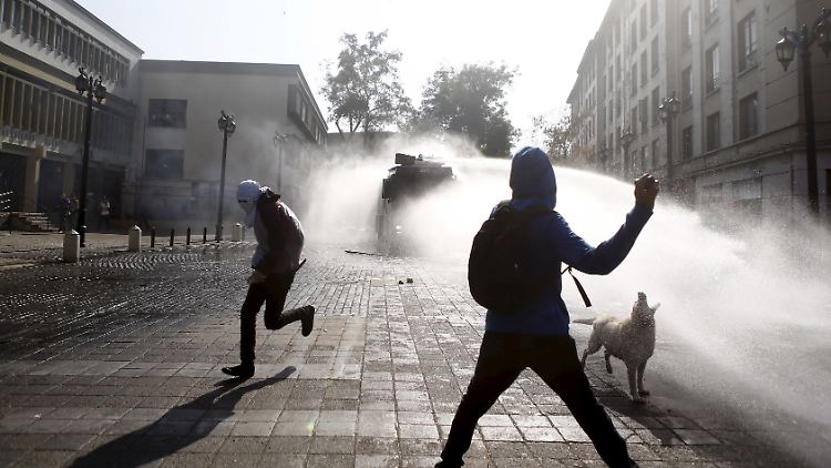 Wut gegen die Staatsmacht: In den Straßen von Santiago geht die Polizei mit Wasserwerfern gegen vermummte Randalierer vor.