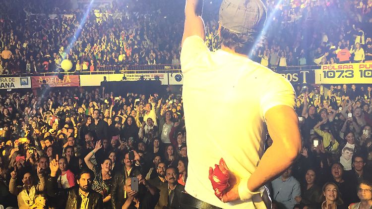 Enrique Iglesias versteckt seine blutende Hand hinter dem Rücken.