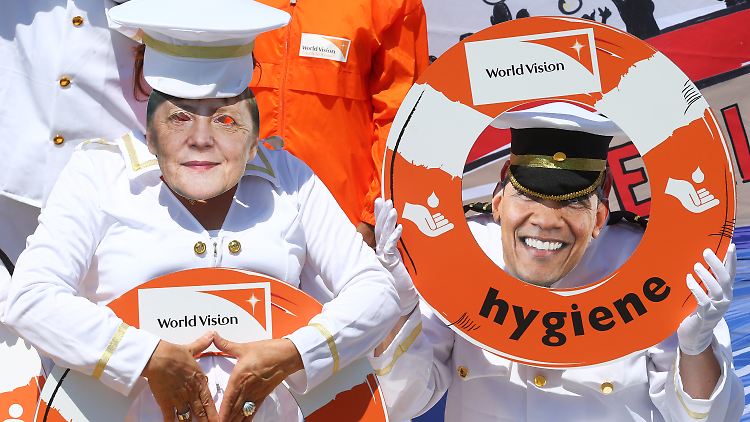Mitglieder von "World Vision" demonstrieren in Garmisch-Partenkirchen mit den Masken Merkels und Obamas.