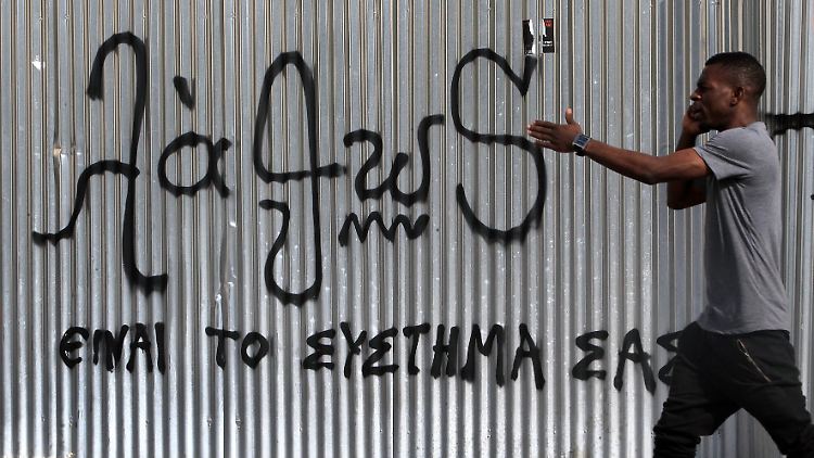 Ein Passant in Athen spaziert an einem Graffiti entlang, auf dem steht: "Unser System ist falsch". Was genau der Graffiti-Künstler damit aussagen wollte, bliebt offen.