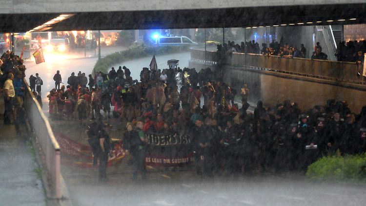 Demonstranten flüchten in Garmisch-Partenkirchen vor einem Gewitter unter eine Brücke.