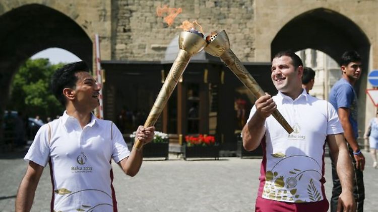 Sänger Faig Agayev (l.) und Judika Elnur Memmedl - beide aus Aserbaidschan - mit der Flamme der Spiele.