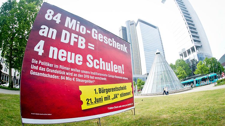 Der Protest hat sich formiert: Plakat mit der Aufschrift "84 Mio-Geschenk an DFB = 4 neue Schulen!" in der Innenstadt von Frankfurt.