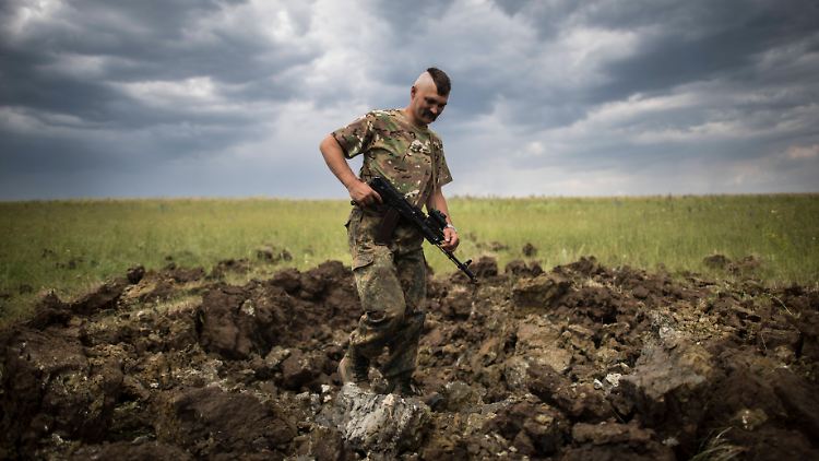 Ein ukrainischer Soldat untersucht den Krater auf einem Feld nach einem Granateinschlag.