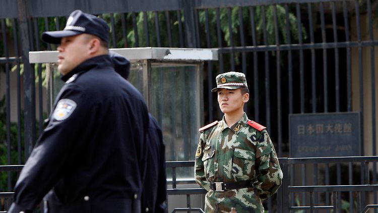 Ein chinesischer Polizeioffizier und ein Japaner, der vor der japanischen Botschaft in Peking Wache steht.