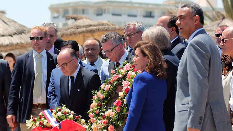 Innenminister de Maizière (Mitte) und sein französischer Amtskollege Cazeneuve legen am Anschlagsort Blumen nieder. 