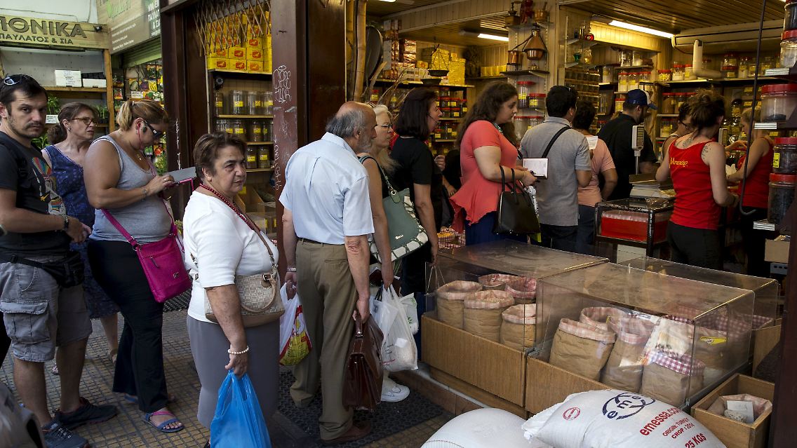 Menschen stehen Schlange vor einem Lebensmittelgeschäft in Athen. Dem Handel geht allmählich das Wechselgeld aus.