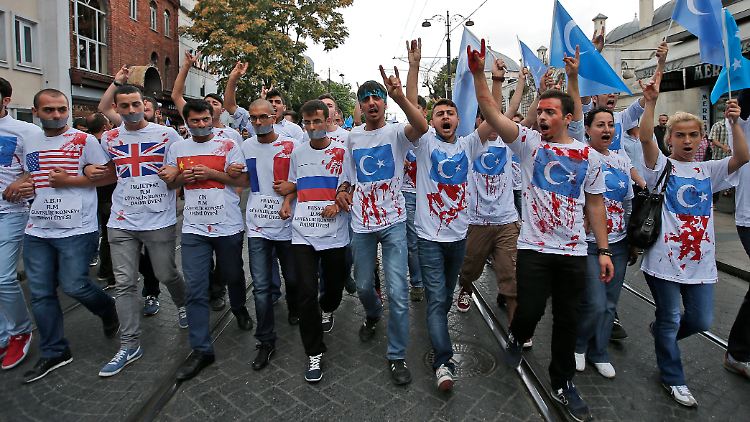 Demonstranten haben ihre T-shirts mit Kunstblut beschmiert, um auf die Behandlung der uigurischen Minderheit in China aufmerksam zu machen.