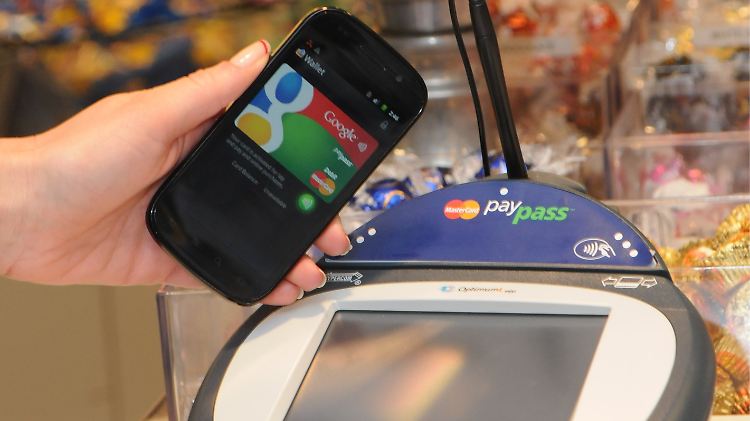 Ein Smartphone wird an einer Supermarkt-Kasse neben ein so genanntes PayPass Gerät zur elektronischen Zahlungsabwicklung gehalten. 