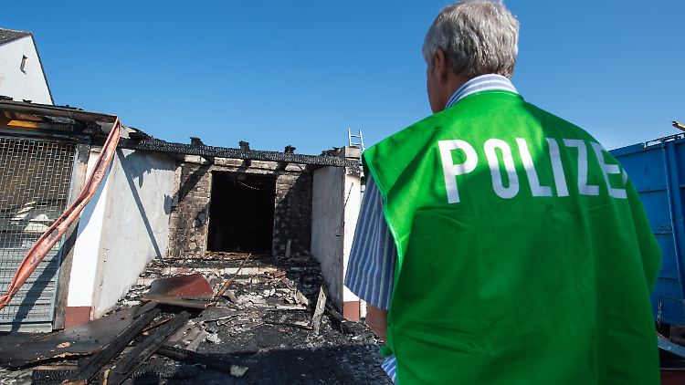 Ein Spurenermittler der Polizei steht vor einem ehemaligen Landgasthof, der in Brand geraten war. 