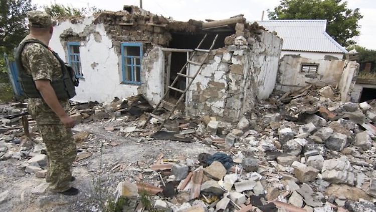 ein ukrainischer Soldat betrachtet die Zerstörungen in Nowotroitskoe, nahe der Frontlinie.