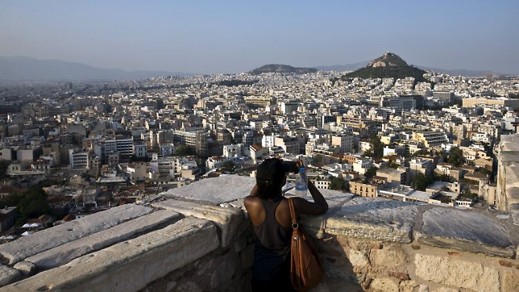 Vom Hügel der Akropolis blickt eine Touristin über Athen.