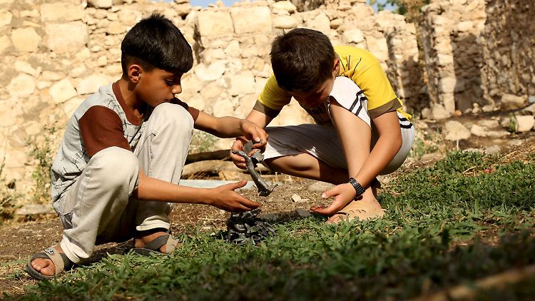 Zwei Jungen spielen nach den Luftangriffen der türkischen Armee in der Provinz Dohuk mit Metallteilen aus einem Bombenkrater.