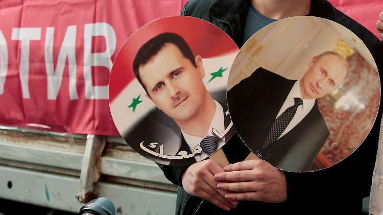 Ein Demonstrant in Moskau hält Fotos von Assad und Putin in der Hand. Lange galt die russische Rückendeckung für das syrische Regime nahezu bedingungslos.