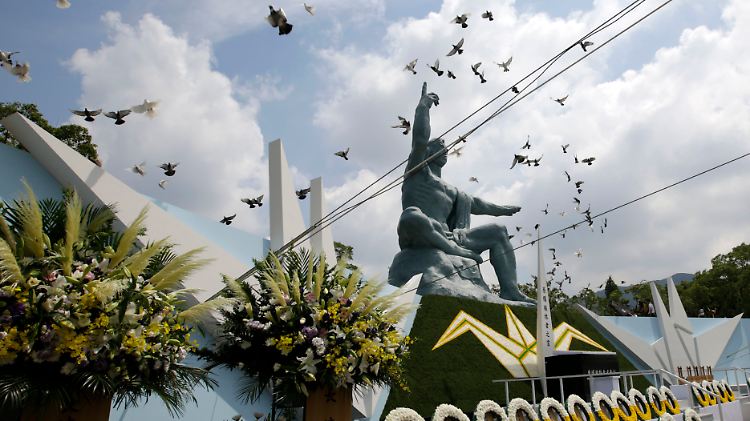Bei der Gedenkveranstaltung fliegen Tauben über die Friedenstatue in Nagasaki.