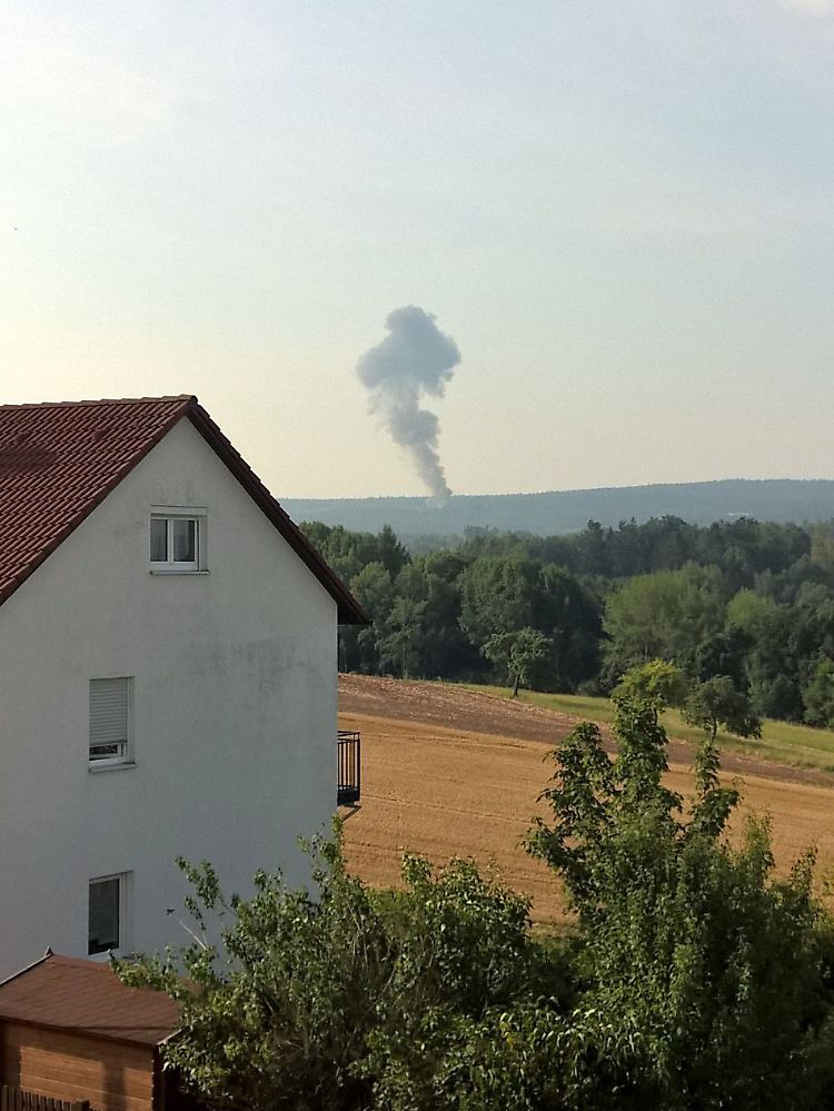 Schrecksekunde am Morgen: Nach dem Absturz der F-16 steigt eine Rauchwolke über dem Wald bei Engelmannsreuth auf; im Vordergrund ein Haus, das zur Ortschaft Creußen gehört.