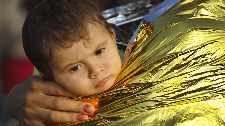 Eine Mutter hüllt ihr Kind nach der Ankunft auf der griechischen Insel Kos in eine Rettungsdecke. Auf der kleinen Insel sind in diesem Jahr bereits 124.000 Flüchtlinge angekommen