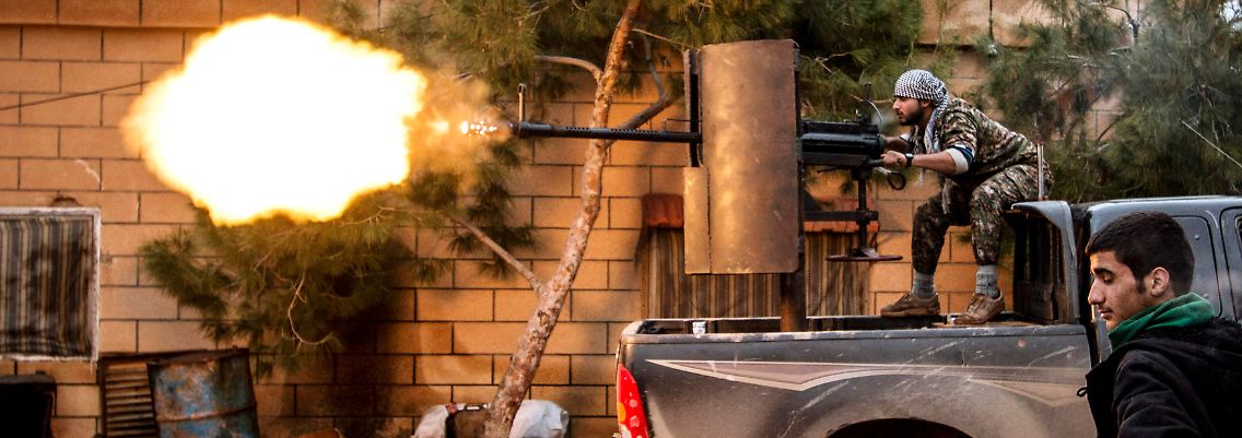 Ein YPG-Kämpfer feuert ein Flak-Geschütz auf Kämpfer des IS.