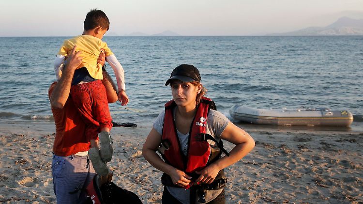 Ankunft im Schlauchboot: Eine junge syrische Familie ist auf Kos angelandet und zieht erschöpft die Schwimmwesten aus.