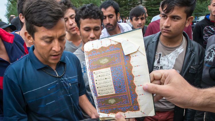 Unter dem Ruf "Allah ist groß" zeigen Muslime vor der Erstaufnahmestelle in Suhl einen zerrissenen Koran.