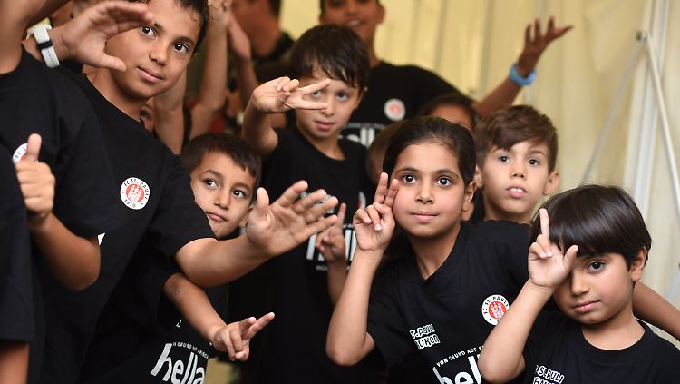 Kurz bevor sie mit den Spielern auf den Rasen laufen posieren Flüchtlingskinder mit St. Pauli-T-Shirts.