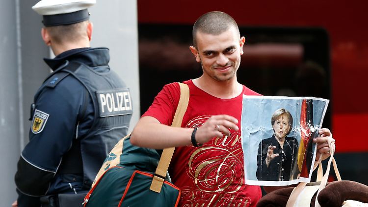 Nach seiner Ankunft in München zeigt ein Flüchtling ein Bild von Angela Merkel. "Die Neuankommenden wollen sich in diesem Land zurechtfinden", sagt Sina Arnold.