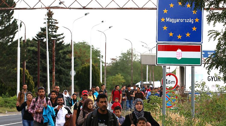 Flüchtlinge überqueren die Grenze zwischen Österreich und Ungarn zu Fuß.