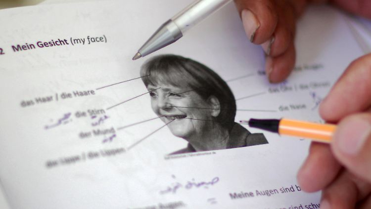 In einer Erstaufnahmeeinrichtung in Limburg an der Lahn lernen Flüchtlinge deutsche Vokabeln wie "Haare" und "Augen" mit Hilfe eines Fotos von Angela Merkel.