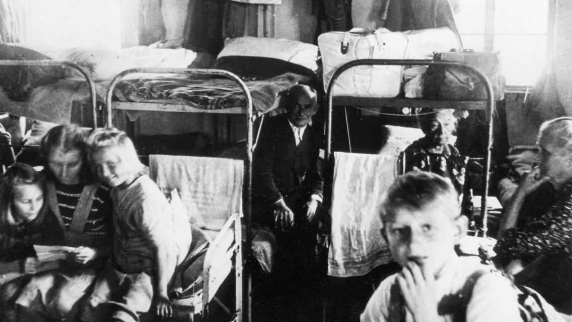 September 1945. Flüchtlinge drängen sich auf dem beengten Platz in einer Notunterkunft des Lagers Friedland bei Göttingen.